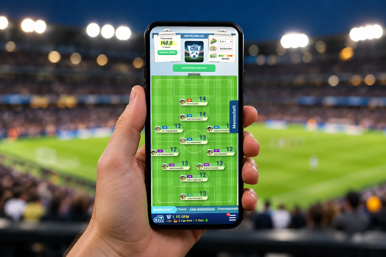 Smartphone mit der Aufstellung im OFM, im Hintergrund ein Stadion bei Flutlicht